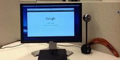 a desktop computer sitting on top of a white desk in an office cubicle,