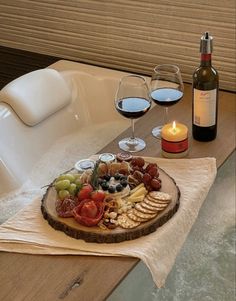 a wine bottle and two glasses of wine sit next to a platter of food