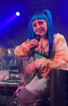 a woman with blue hair sitting in front of a microphone