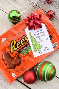 an orange bag filled with reese's christmas tree treats and ornaments on top of a wooden table