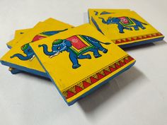 three wooden coasters with painted elephants on them