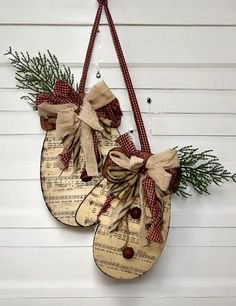 two wooden spoons decorated with ribbons and pine cones hang on the wall next to each other