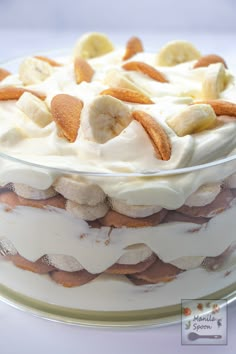 there is a cake with bananas and cream frosting on the top, sitting on a glass platter