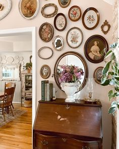 there are many plates hanging on the wall above a dresser and table in this dining room