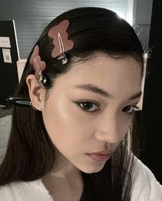 a woman with two hair clips on her head looking at the camera while wearing a white shirt