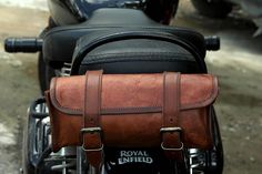 a brown leather bag sitting on the back of a motorcycle