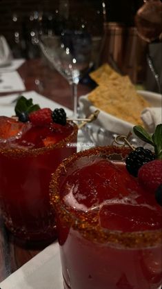 two glasses filled with fruit sit on a table