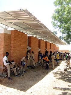 a group of people standing next to each other near a brick building with a white awning