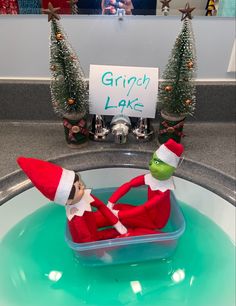 an elf is sitting in the sink with a sign that says grin lake