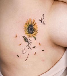 a woman's stomach with a sunflower tattoo on her belly and two butterflies flying around