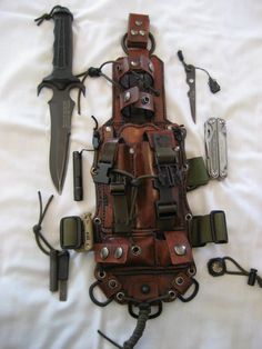 an assortment of knives and sheaths laid out on a bed