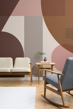 two chairs and a table in front of a wall with an abstract design on it