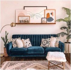 a living room with a blue velvet couch, rug and potted plants on the wall