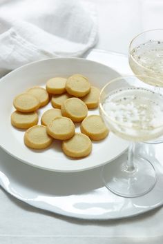 a white plate topped with cookies next to a glass of wine