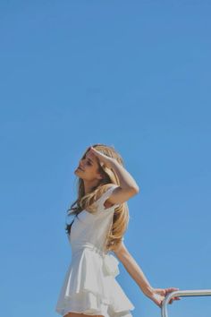 a woman in a white dress is holding her hair