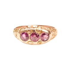 An incredible Victorian Etruscan 12K pink sapphire three-stone band ring. Features engraved floral and scroll motifs with three round-cut pink sapphires. The stones sit flush in round jagged settings and really pop against the gold band.  This ring has not been appraised but the stones are believed to be natural and remain in great condition with minimal surface wear. The gold facade has a polished finish with only minor tarnishing. There are no notable hallmarks or makers mark but the gold has Pink Three-stone Sapphire Jewelry, Pink Sapphire Three-stone Jewelry, Pink Sapphire Three Stone Jewelry, Antique Pink Jewelry With Rose Cut Diamonds, Antique Pink Rose Cut Diamond Jewelry, Victorian Pink Rose Cut Diamond Jewelry, Fine Jewelry Pink Three Stone Jewelry, Three Stone Pink Sapphire Jewelry Gift, Fine Pink Three Stone Jewelry