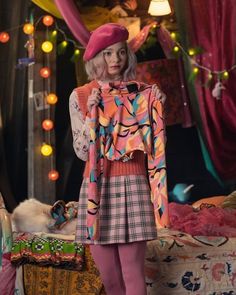 a woman standing in front of a bed wearing a colorful dress and pink tights