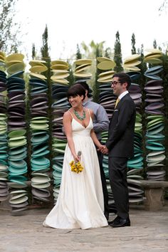 a man and woman standing next to each other in front of stacks of paper plates