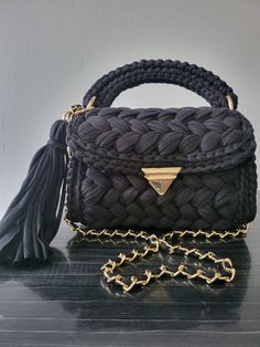 This handbag is made 100% by hand, it's elaborated with cotton thread with dimensions 9"L 7"H 3"W (not including the handle), the handle is hand sown and it also includes a gold chain for the option of it being a handbag or a crossbody.It has a removable decorative tassel.The length of the chain is 43.3" if you would like a different length chain you may get in contact with me. This beautiful crochet bag is the perfect accessory for your favorite outfit. You'll look and feel gorgeous while also having a unique accessory made by hand. It's a perfect gift for any special occasion. NOTES: DOES NOT have inner cover. The clasps can vary from the ones in the images. AFTER CARE Do not machine wash, Do not iron. Clean with a damp cloth or sponge. THANK YOU FOR VISITING MY SHOP ❣️❣️ Capri Luxury, Wedding Party Bags, Knit Purse, Handmade Backpacks, Crochet Purse Patterns, Luxury Bag, Purse Patterns, Black Shoulder Bag, Crochet Bags