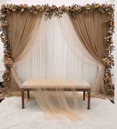 a bench with sheer curtains and flowers on it