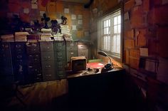 a room with many filing cabinets and a desk in the corner, all lit up by a window