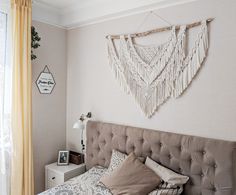 a bed sitting in a bedroom next to a window with curtains on the windowsill