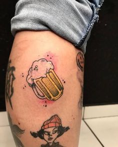 a person with a tattoo on their leg holding a beer mug and wearing a hat