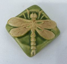 a green and yellow dragonfly tile on a white surface