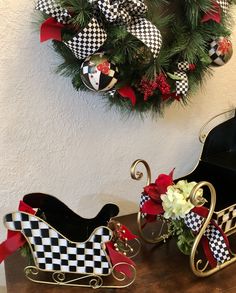 two christmas decorations sitting on top of a wooden table next to a sleigh