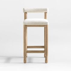 a wooden bar stool with a white upholstered seat and back rest on an isolated background