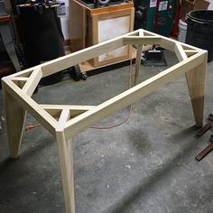 a wooden table sitting on top of a floor next to a pile of woodworking tools