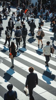 many people are walking across the crosswalk