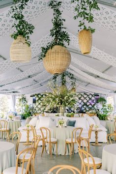 tables and chairs are set up in a tent for an outdoor wedding reception with hanging planters on the ceiling