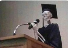 a skeleton wearing a graduation cap and gown stands at a podium with a microphone in front of him