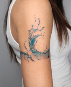 a woman's arm with a blue and white wave tattoo on her left shoulder