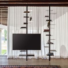 a flat screen tv sitting on top of a wooden stand in front of a window