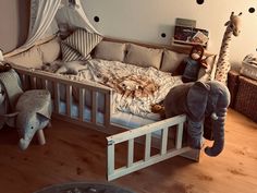 a child's bed with an elephant stuffed animal in the middle and other toys