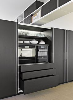 an open cabinet in the middle of a room with shelves and cupboards on each side