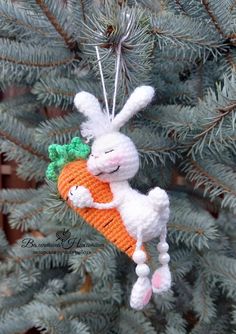 an ornament shaped like a bunny holding a carrot hanging from a pine tree