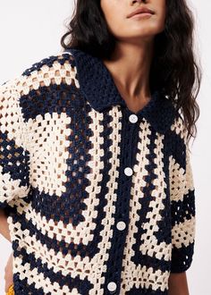 a woman is wearing a crocheted jacket with buttons on the collar and sleeves