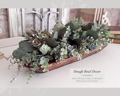 a wooden bowl filled with green plants on top of a table