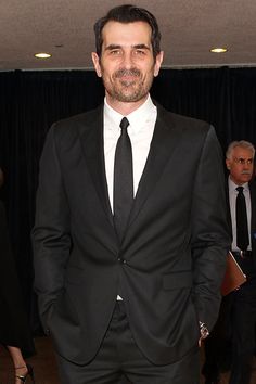 a man in a suit and tie standing next to other people at an awards event