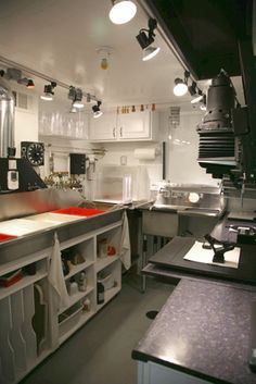 a large kitchen with lots of counter space and lights on the ceiling, along with white cabinets