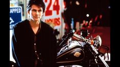 a woman standing next to a motorcycle in front of a store sign and another bike behind her