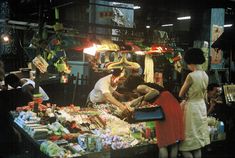 people are shopping at an outdoor market in the dark