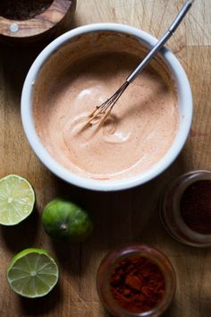 a bowl filled with chocolate and limes on top of a wooden table next to two bowls