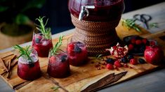 three glasses filled with red wine and garnishes on a wooden cutting board