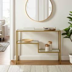 a living room with white walls and a gold framed mirror on the wall above a console table