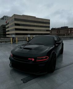 a black sports car parked in front of a building on a parking lot with no one around it