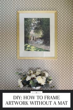 a painting hanging on the wall next to a vase with flowers in front of it